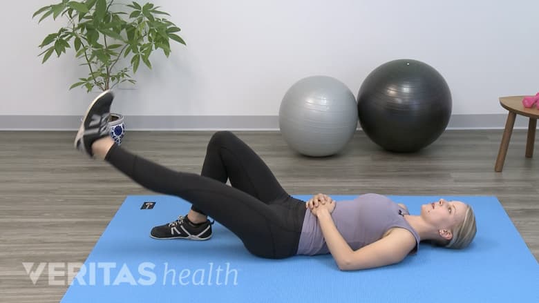 Therapist lying on her back outdoors doing a supine leg raise