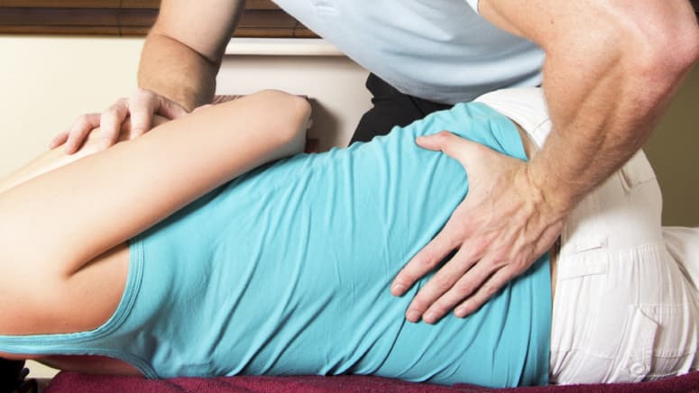 Chiropractor manipulating a patient&#039;s lumbar spine.