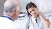 Woman grabbing her neck in pain while talking with a doctor