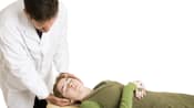 Chiropractor adjusting a supine patient&#039;s cervical spine.