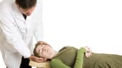 Chiropractor adjusting a supine patient&#039;s cervical spine.
