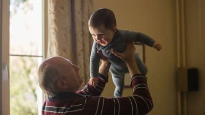 Elderly man lifting baby
