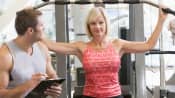 Woman doing arm exercises with a trainer in a gym.