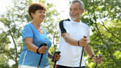 Two elderly people walking with cross country sticks.