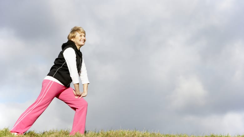 Elderly woman stretching outdoors.