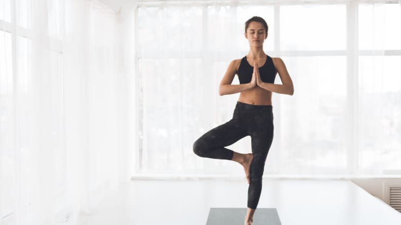 Woman performing the tree yoga pose on a yoga mat.