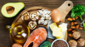 Spread of healthy foods including broccoli, salmon, eggs, olive oil, chia seeds, and avocado