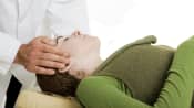 Chiropractor adjusting a supine patient&#039;s spine.