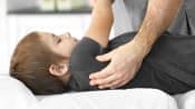 Physical therapist stretching a child&#039;s upper back