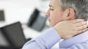 Man sitting at his computer grabbing neck in pain