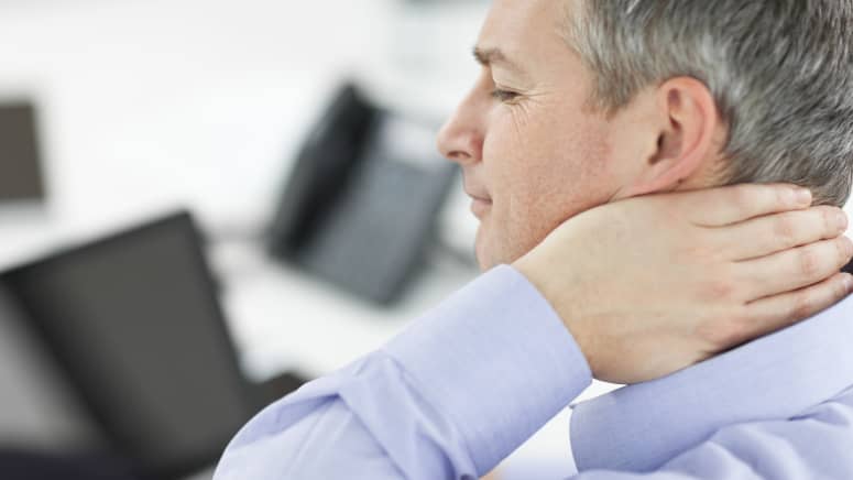 Man sitting at his computer grabbing neck in pain