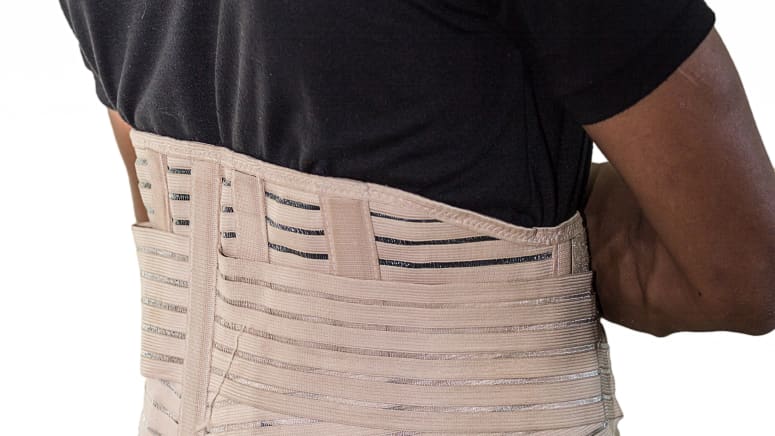 Man&#039;s torso with a lower back brace over his shirt
