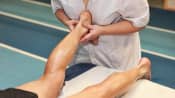 Therapist doing myofascial release therapy on a man&#039;s ankle