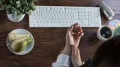 Woman&#039;s hands at a keyboard, one massaging the other