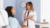 Patient in hospital bed talking with doctor