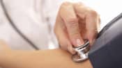 Doctor taking a patient&#039;s blood pressure with stethoscope and blood pressure cuff.
