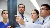 Doctors examining x-rays of patient&#039;s spine.