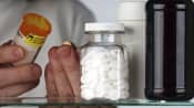 A man holding medication and reading the pill bottle