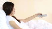 Woman watching tv propped up in bed