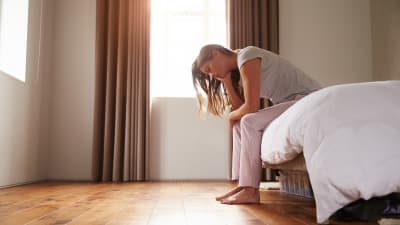Woman sitting on bed suffering from insomnia and depression